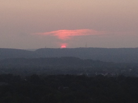 the orange sun sets over gray hills