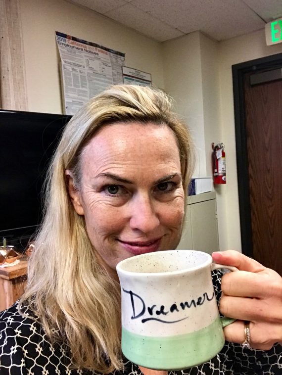 woman smiling holding coffee mug up to her face